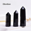 Three black obsidian crystal points standing upright on a white surface.