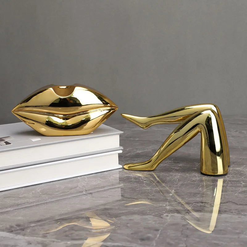 A gold faux finish sculpture of a human mouth resting on a stack of white books.