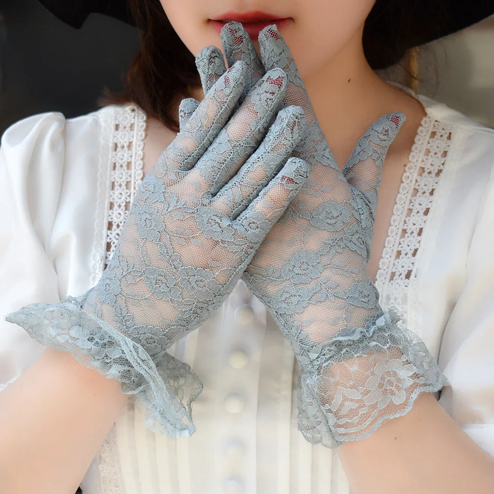 A pair of light blue sheer lace gloves worn by a woman, featuring delicate floral patterns.
