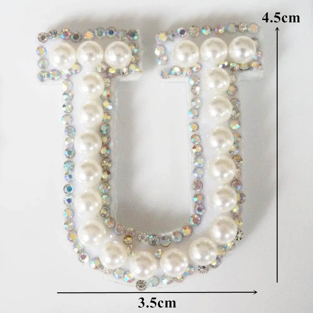 A white alphabet letter U made of pearl and rhinestone patches for clothing