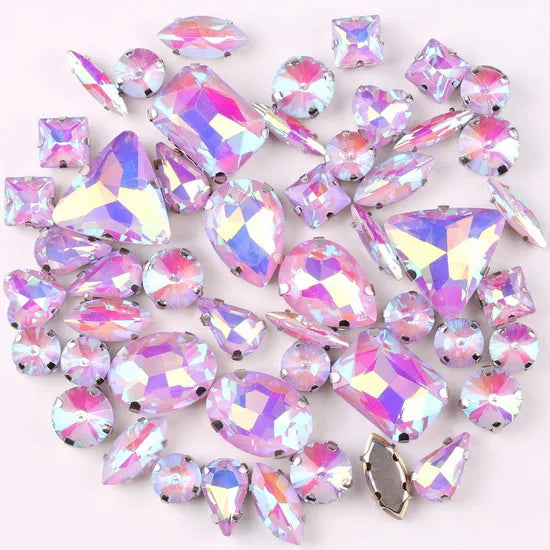 A mix of iridescent silver claw setting glass rhinestones in jelly candy AB colors scattered on a white background.