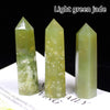 Three light green jade crystal points displayed on a white surface.