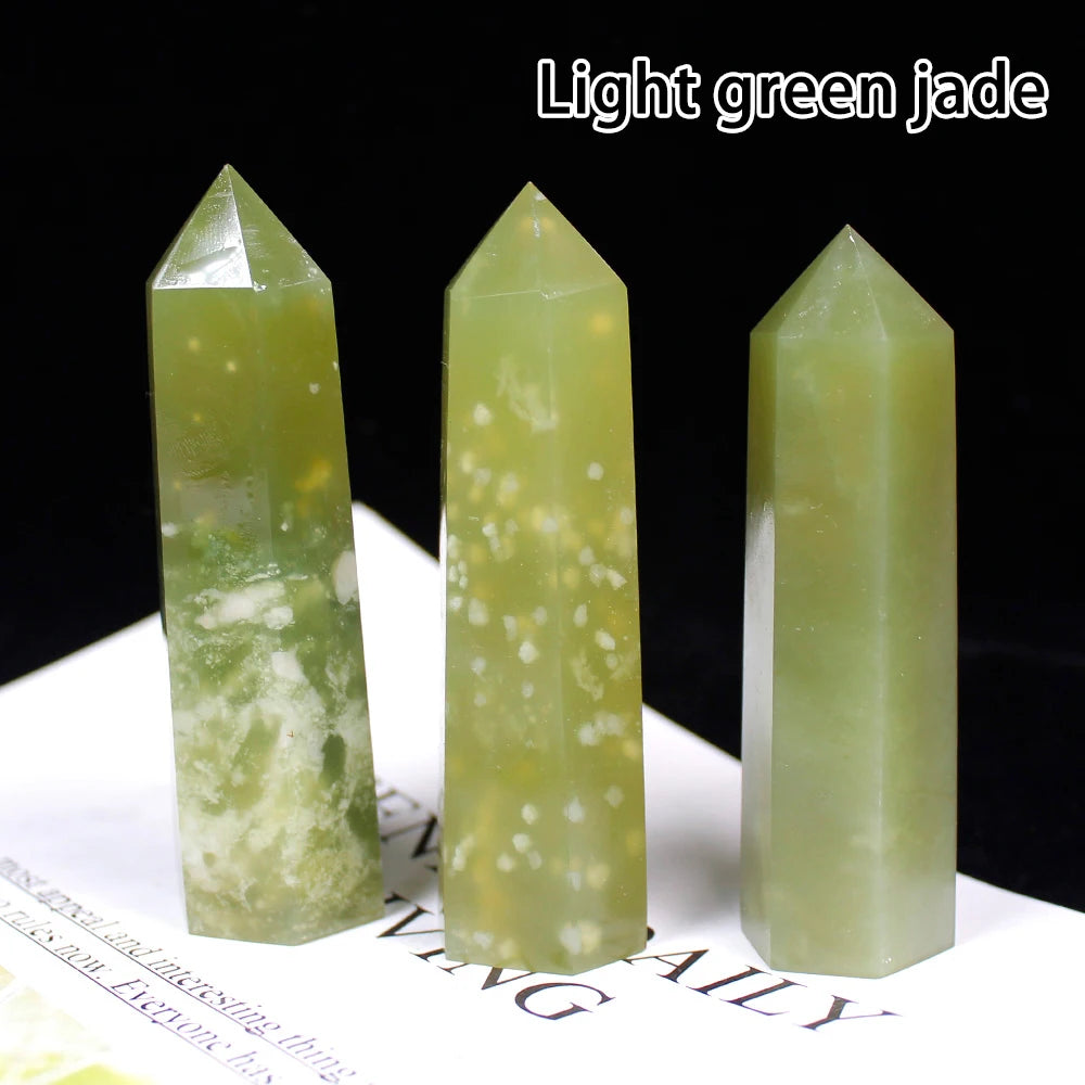 Three light green jade crystal points displayed on a white surface.