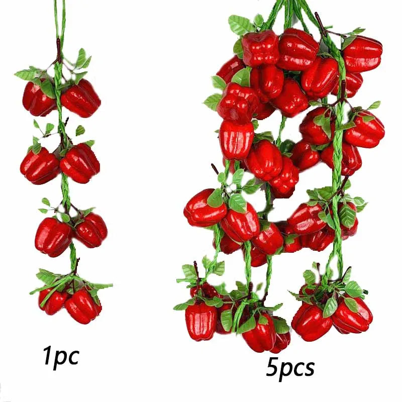 A string of bright red artificial fruits and vegetables used for decoration or photography.