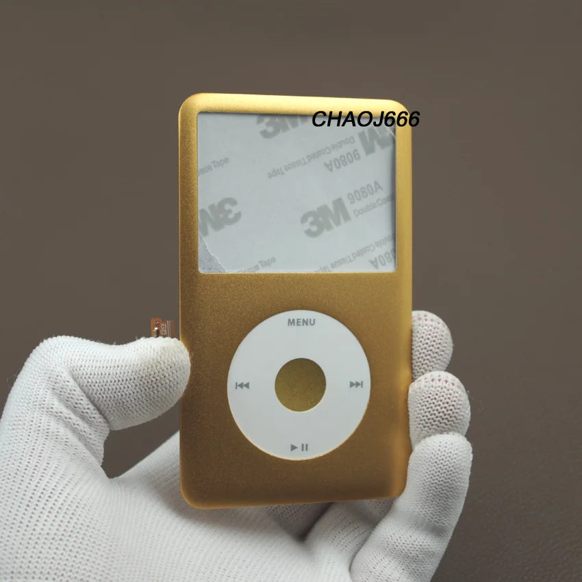 Une main tient un kit de réparation de face avant d'un iPod Classic de couleur or sur un fond neutre.
