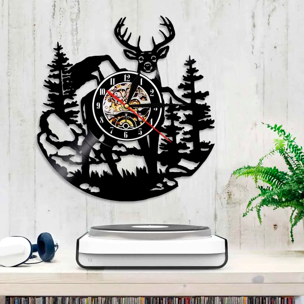 A black silhouette of a deer head and forest trees forms the design of a wall clock.