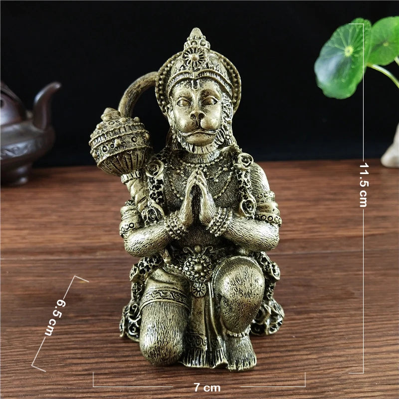 Bronze Hanuman statue figurine with hands folded in prayer sitting on a wooden surface.