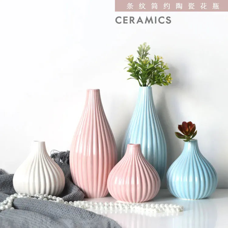 A collection of elegant ceramic flower vases in pink and blue tones displayed on a white surface.