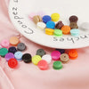 Assorted snap buttons in various colors and sizes arranged on a white plate.