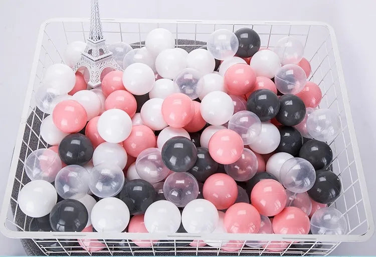 A clear plastic basket filled with a 50-pack of colorful, translucent, and opaque spherical balls in pink, white, and black.