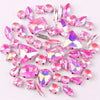 A mix of silver claw setting glass rhinestones in jelly candy AB colors scattered on a white background.
