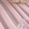 Soft pink sheer chiffon fabric draped in vertical pleats with white roses in the background