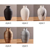 Five variations of a modern ceramic flower vase in black, white, gold, and silver finishes.