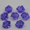 A collection of twelve faceted purple acrylic crystals or decorations arranged on a light gray surface.