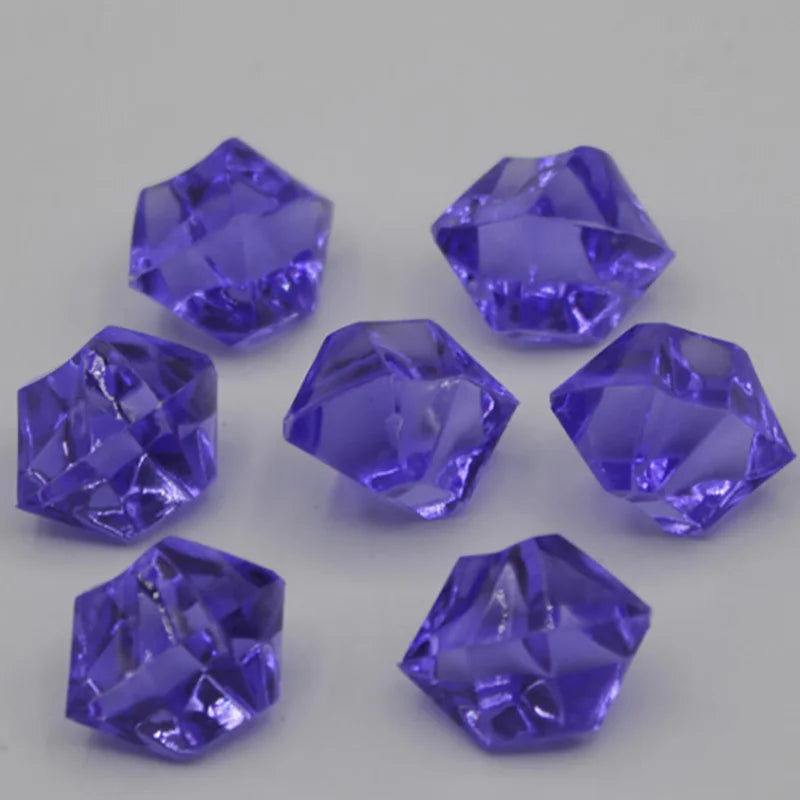 A collection of twelve faceted purple acrylic crystals or decorations arranged on a light gray surface.