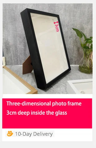 A black three-dimensional photo frame with 3cm deep glass inside, displayed on a light surface.