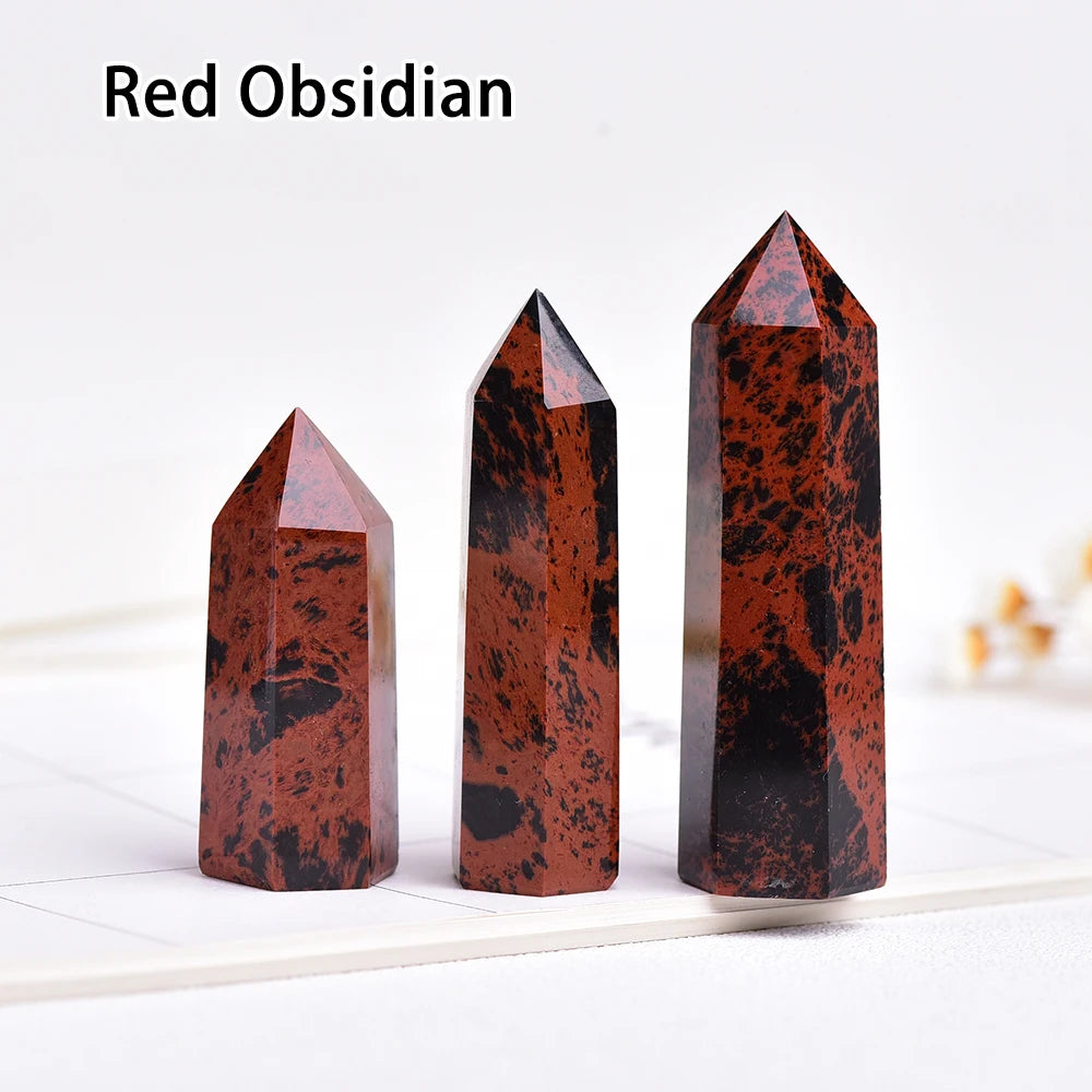 Three red obsidian crystal point prisms standing upright on a white surface.
