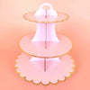 A pink cardboard cupcake stand with three tiers, featuring scalloped edges and a gold rim.