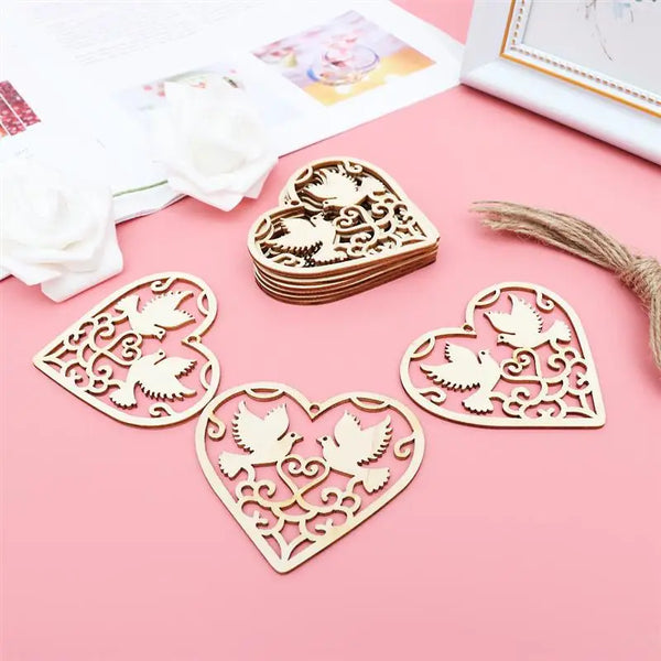 A collection of ten wooden heart-shaped hanging ornaments with intricate cutouts arranged on a pink surface.