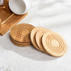A set of wooden coasters and a ceramic coffee mug with a bamboo wood stand on a white surface.
