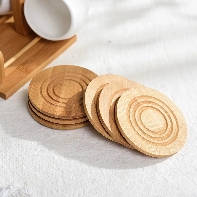 A set of wooden coasters and a ceramic coffee mug with a bamboo wood stand on a white surface.