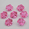 Several faceted pink acrylic crystals or decorations scattered on a white surface.