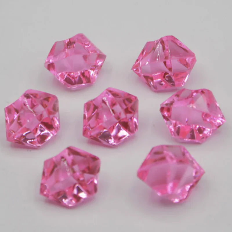 Several faceted pink acrylic crystals or decorations scattered on a white surface.