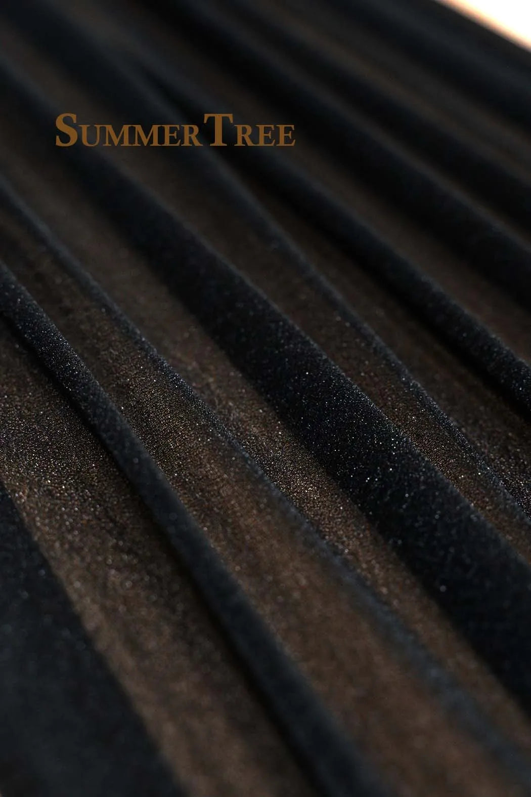 Close-up texture of dark sheer chiffon fabric draped in vertical folds.
