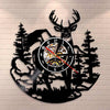 Black silhouette wall clock featuring a deer head and elk antlers against a brick background.