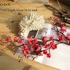 Artificial silk cherry blossom branches with pink flowers and a white fluffy element displayed on a wooden surface.