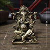 A handcrafted gold-colored resin statue of Lord Ganesha sitting on a pedestal.
