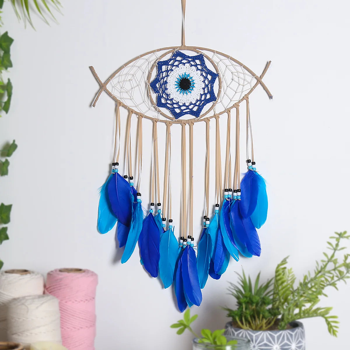 Handmade boho evil eye dream catcher wall decor featuring a woven circle and blue feathers