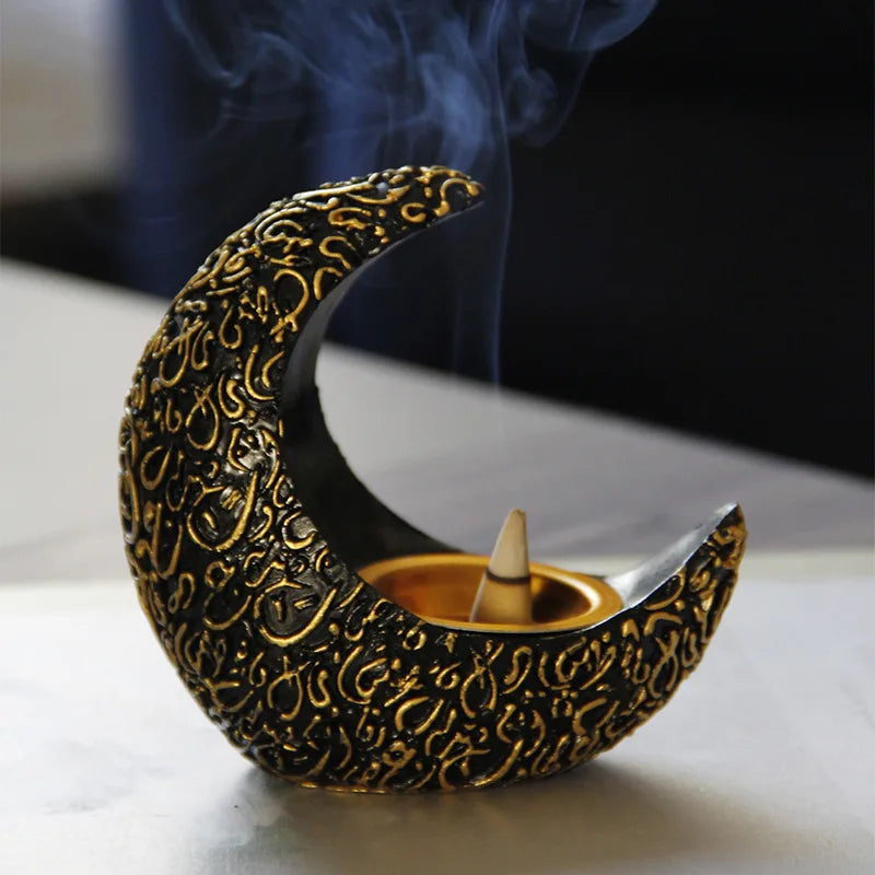 A golden crescent shaped resin incense burner with smoke rising above it.