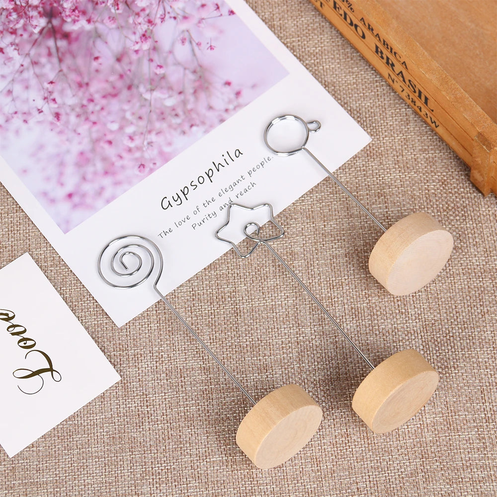 A set of vintage wooden photo frames with silver wire stands displayed on a beige fabric next to a book.