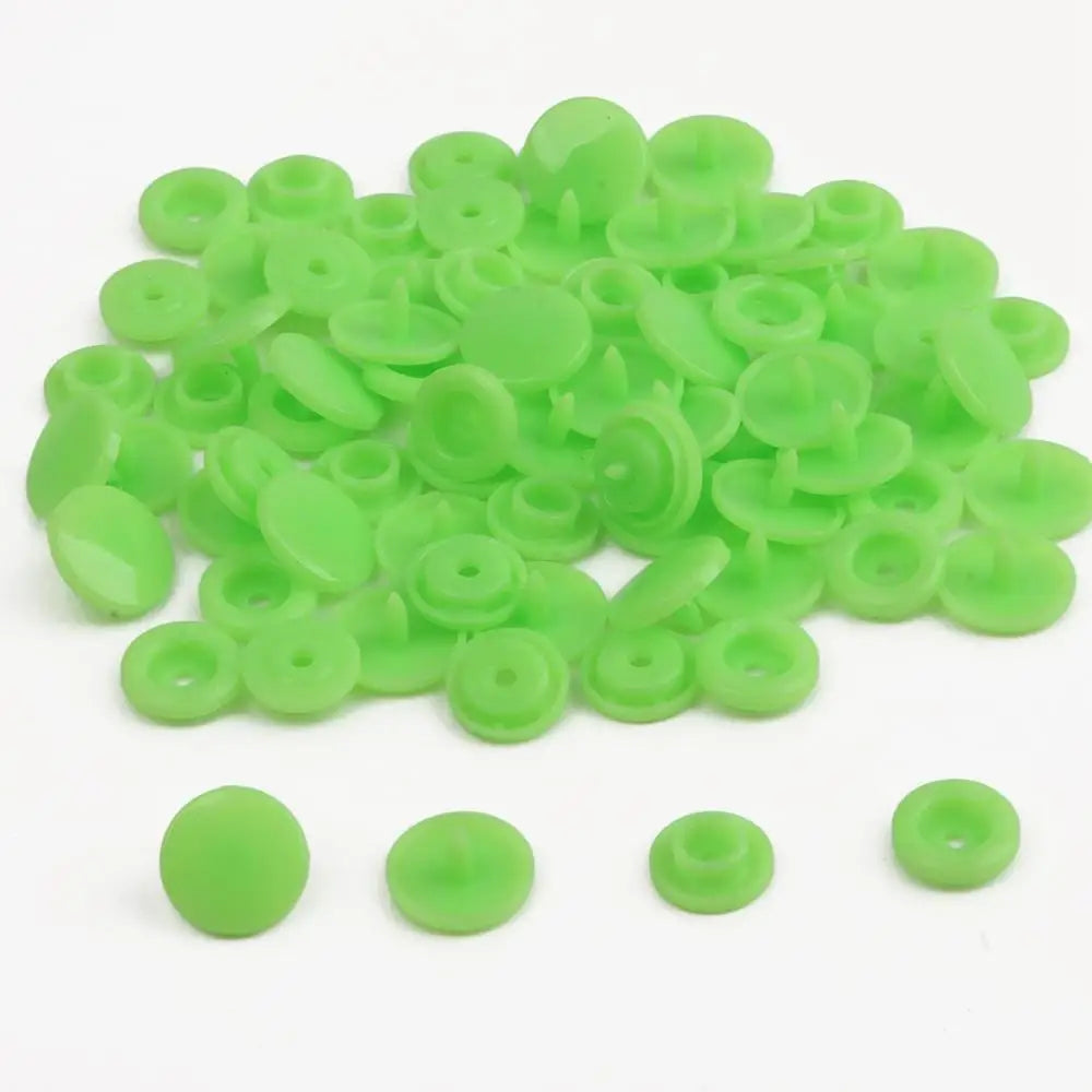 A pile of assorted light green snap buttons, measuring 12mm and 10.5mm, for crafting.