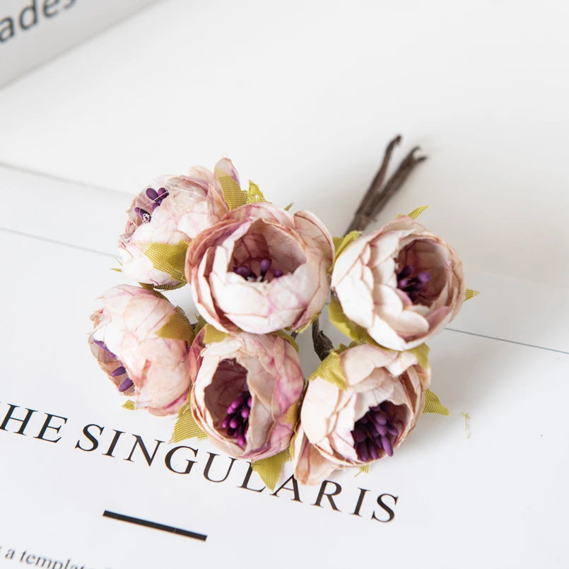 Eine Ansammlung künstlicher rosa und lila Rosen auf einer weißen Oberfläche.