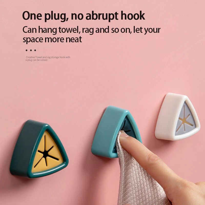 A hand is shown using a suction cup towel holder hook to hang a towel on a pink wall.