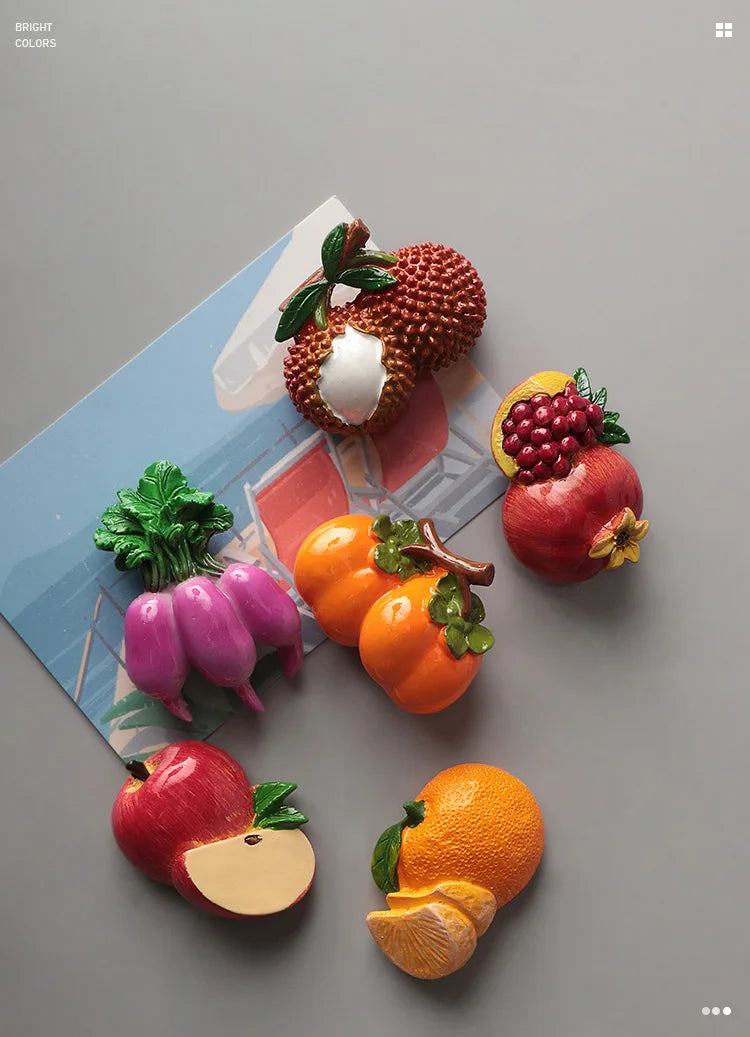 A set of realistic, colorful fruit and vegetable fridge magnets including a pomegranate, citrus fruit, and various colorful p