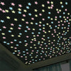 A ceiling decorated with glow-in-the-dark star wall stickers in various pastel colors against a dark background.
