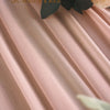 Soft pink chiffon fabric draped in elegant folds with a dark green leaf and peach roses.