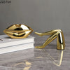 A gold faux finish sculpture shaped like lips resting on a white book.