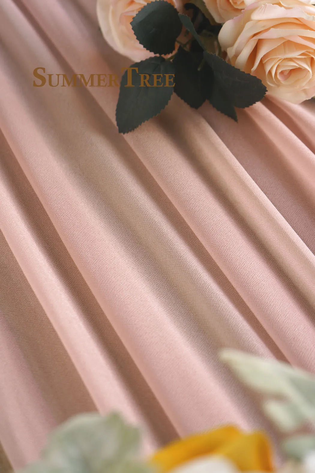 Soft pink sheer chiffon fabric draped in flowing folds with floral accents.
