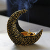 A golden crescent shaped resin incense burner with smoke rising above it.
