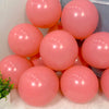 A collection of pink and coral balloons arranged in a box for party decorations.