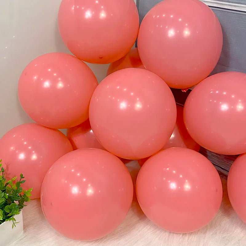 A collection of pink and coral balloons arranged in a box for party decorations.
