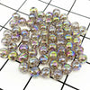 A pile of 50 clear and iridescent acrylic round beads for jewelry making scattered on a black and white grid.