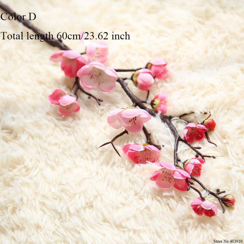 Pink artificial silk cherry blossom branches on a white fluffy surface