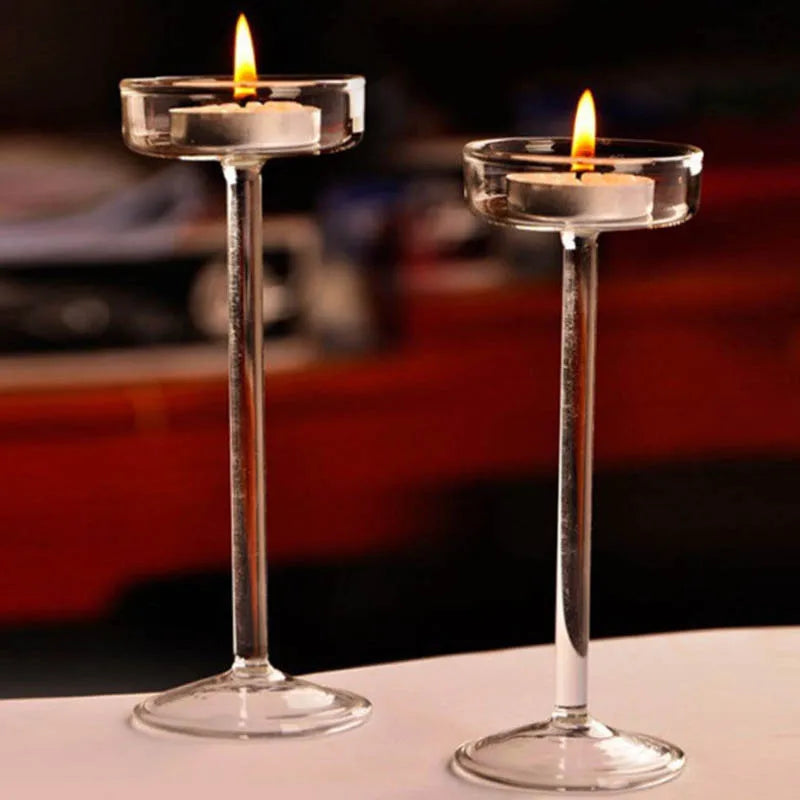 Elegant glass candle holder with a lit candle on a clear glass stem and base.