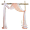 White and peach sheer chiffon fabric drape suspended from a wooden cross for wedding or event decor