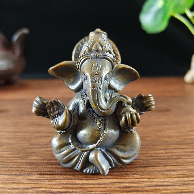 Handcrafted bronze Buddha statue with elephant head sitting pose on a wooden surface.